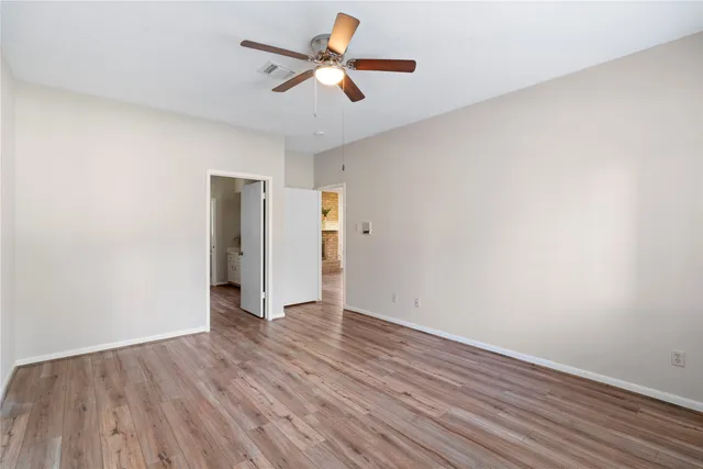 an empty room with wooden floor and a ceiling fan