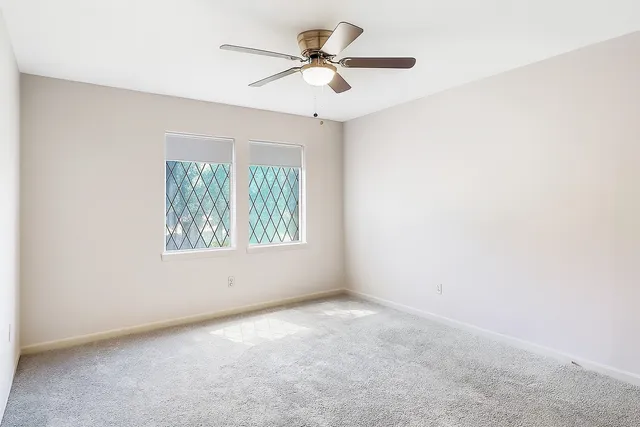 an empty room with a window and a fan