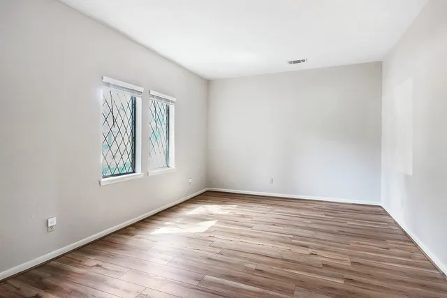 a view of an empty room with wooden floor and a window