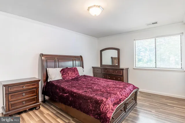 a bedroom with a bed and a dresser next to a window