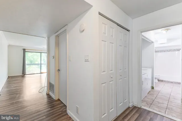 a view of a hallway with wooden floor and closet area