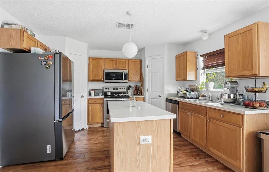 11077 Jenny Wren Road Weeki Wachee, FL 34614 - Photo 10 of 42 a kitchen with stainless steel appliances granite countertop a refrigerator a stove top oven a sink dishwasher and wooden cabinets with wooden floor