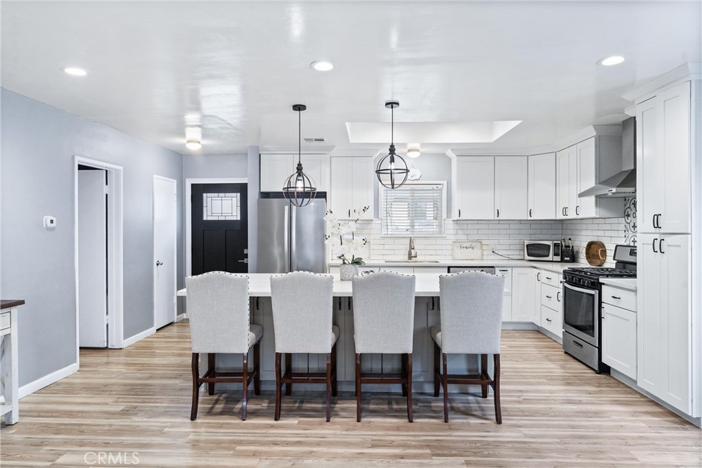 7932 Euclid Avenue Whittier, CA 90602 - Photo 7 of 31 a large kitchen with kitchen island a dining table chairs and white cabinets