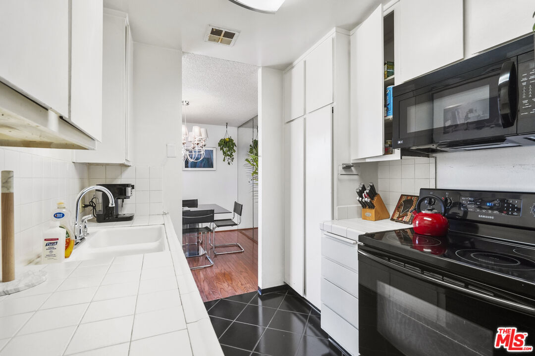 100 South Doheny Drive, Unit 506 Los Angeles, CA 90048 - Photo 6 of 17 a kitchen with a sink a stove and cabinets
