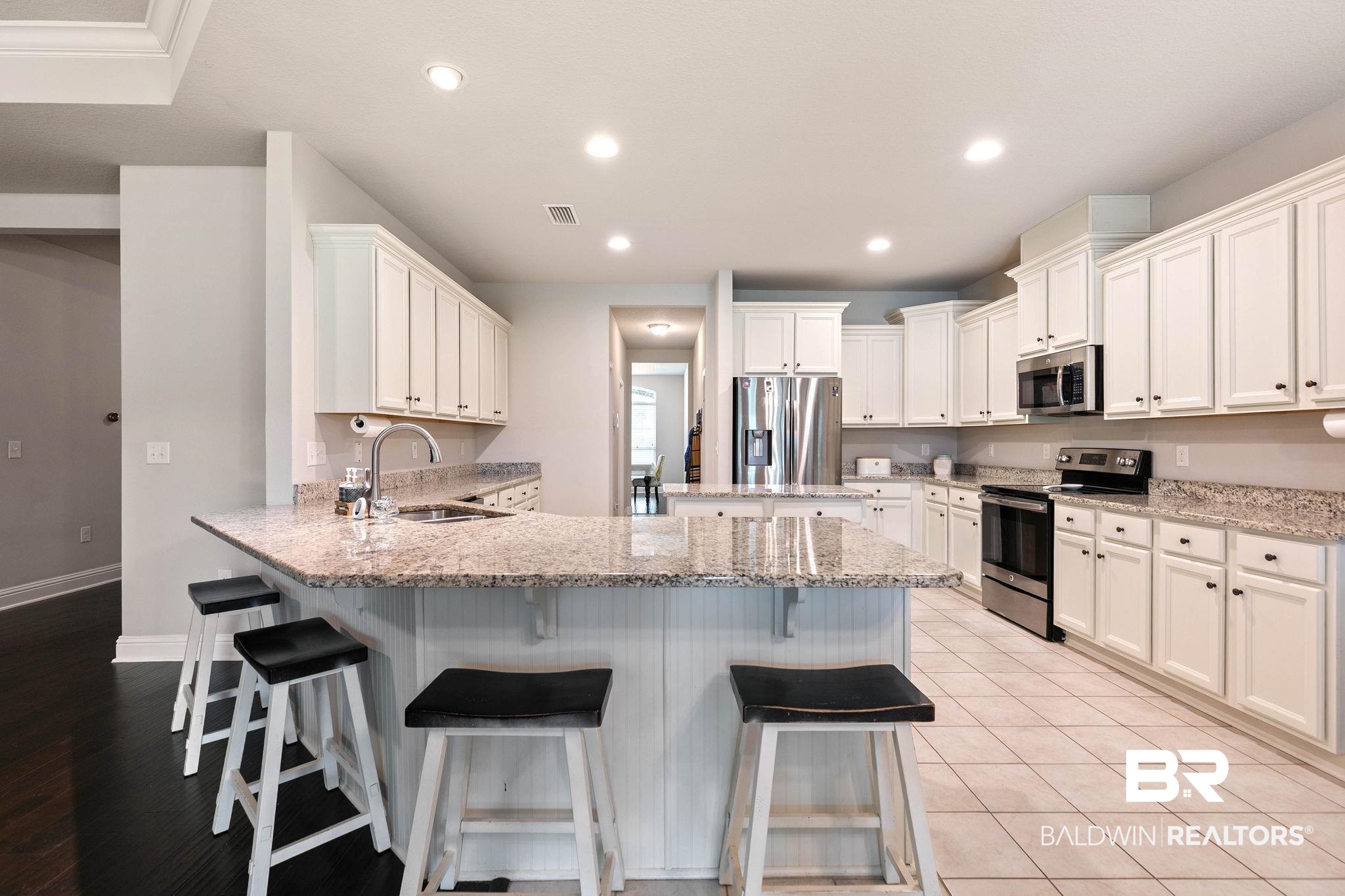 12750 B Jenkins Pit Road Daphne, AL 36527 - Photo 20 of 89 Kitchen with a peninsula, stainless steel appliances, a breakfast bar area, white cabinets, and light stone countertops