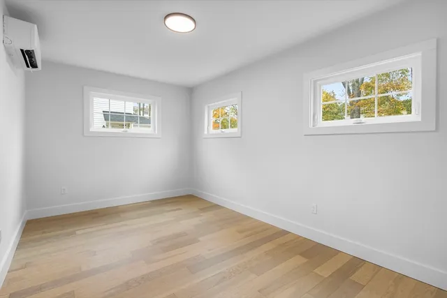 a view of an empty room with wooden floor and window