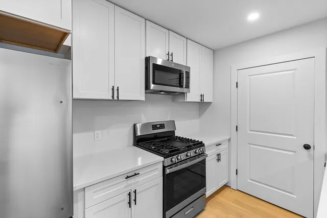 a kitchen with stainless steel appliances granite countertop white cabinets and a stove top oven
