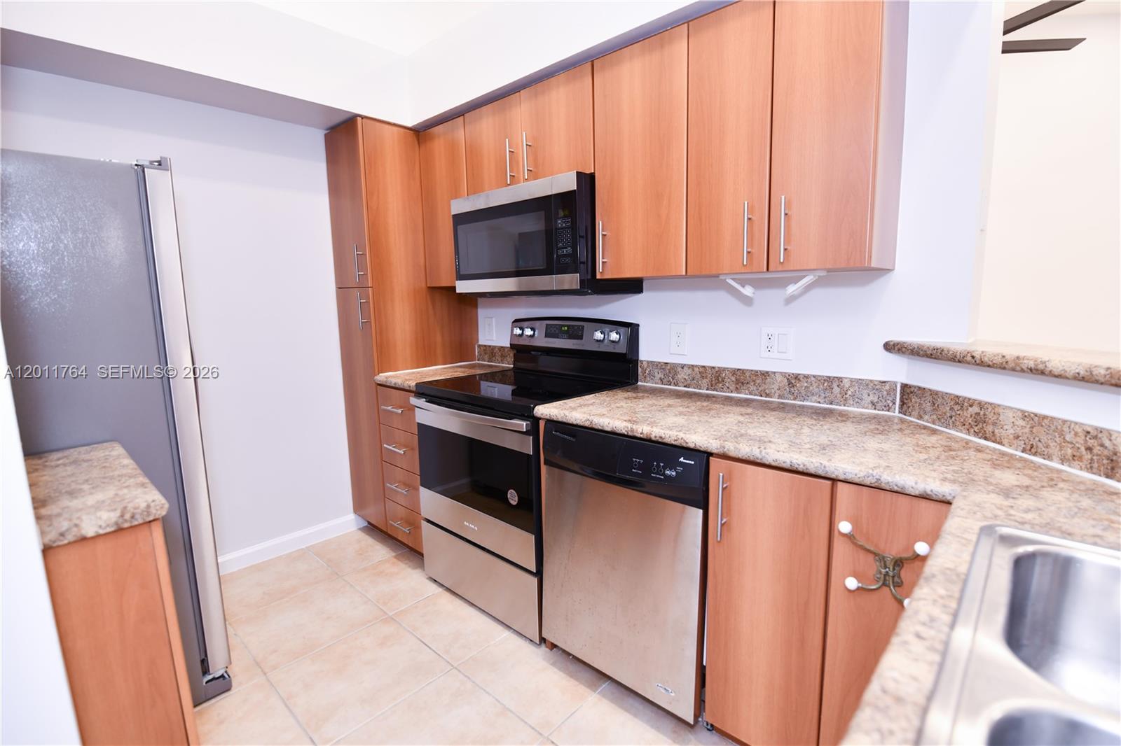 1011 Crystal Way, Unit D Delray Beach, FL 33444 - Photo 7 of 9 a kitchen with granite countertop wooden cabinets stainless steel appliances and a counter space