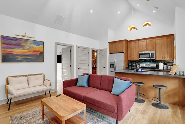 a living room with furniture a rug kitchen view and a window
