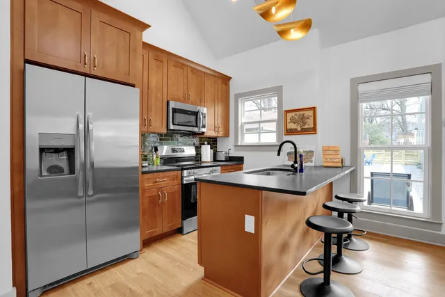 a kitchen with stainless steel appliances granite countertop a refrigerator a stove a sink and a window