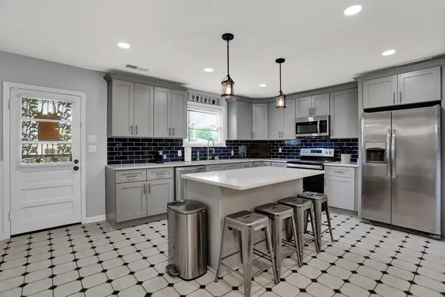 a kitchen with granite countertop a sink cabinets stainless steel appliances and a window
