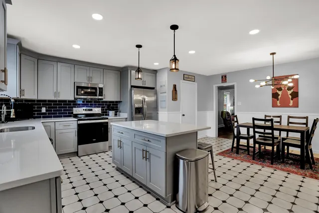 a kitchen with stainless steel appliances kitchen island granite countertop a sink and a refrigerator