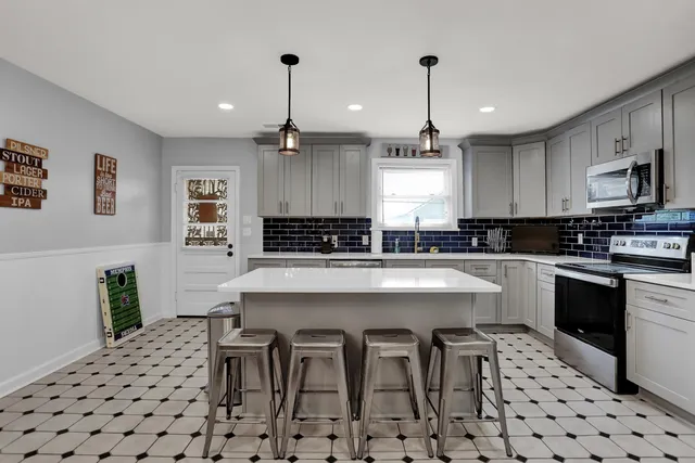 a kitchen with stainless steel appliances kitchen island granite countertop a sink a stove a dining table and chairs