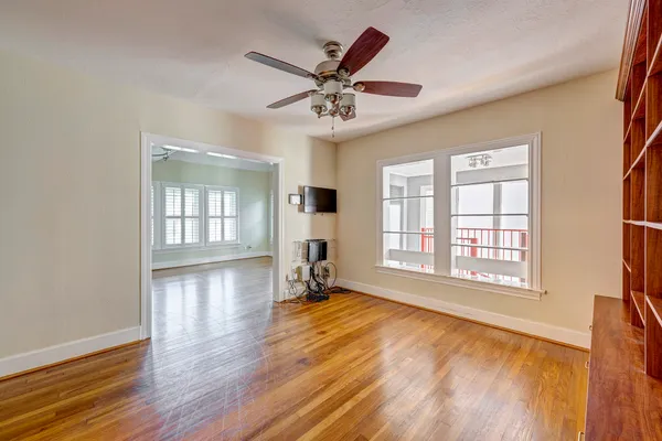 a view of an empty room with window and wooden floor