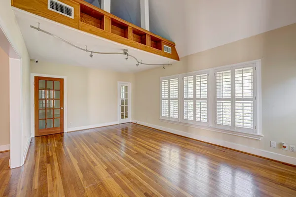 a view of an empty room with wooden floor and a window