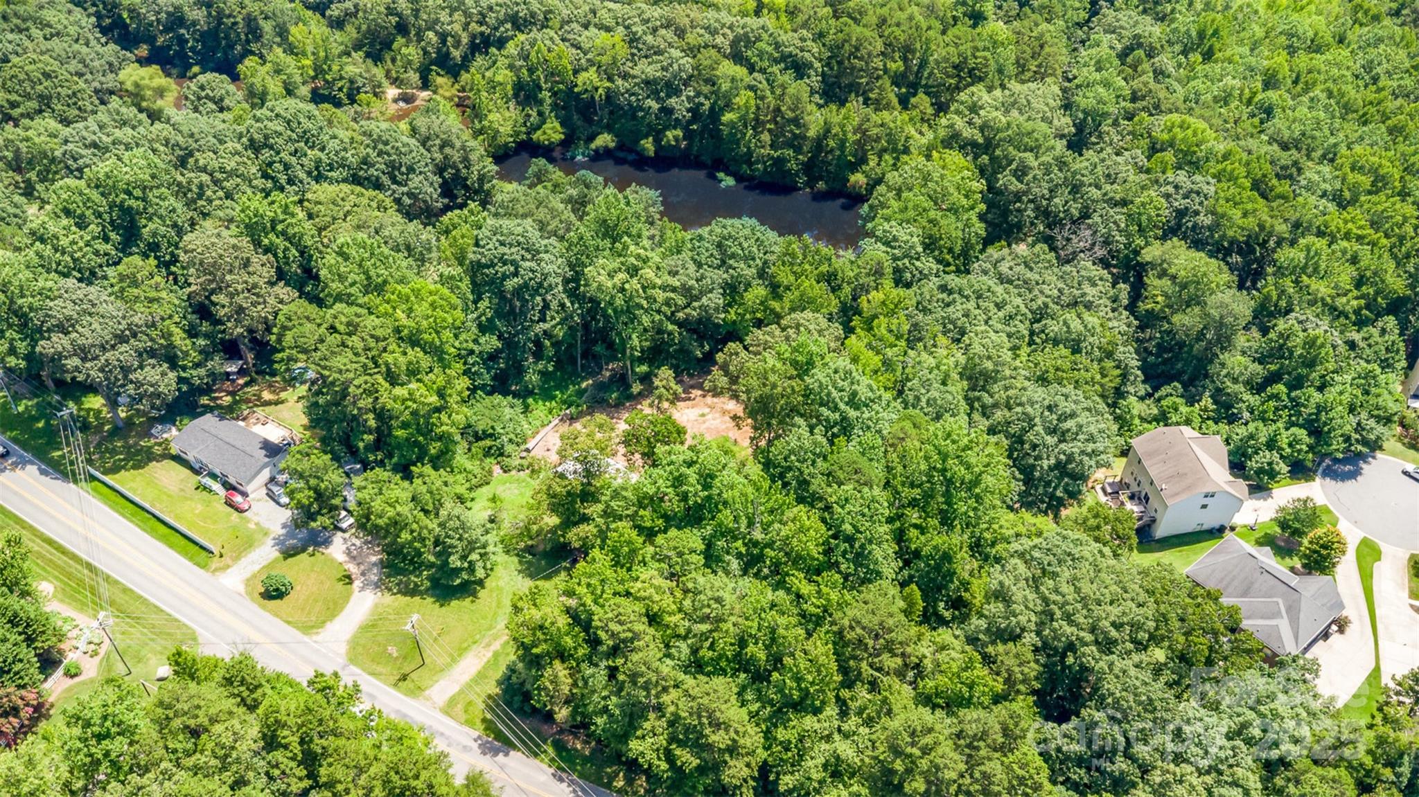 an aerial view of residential house with outdoor space and trees all around