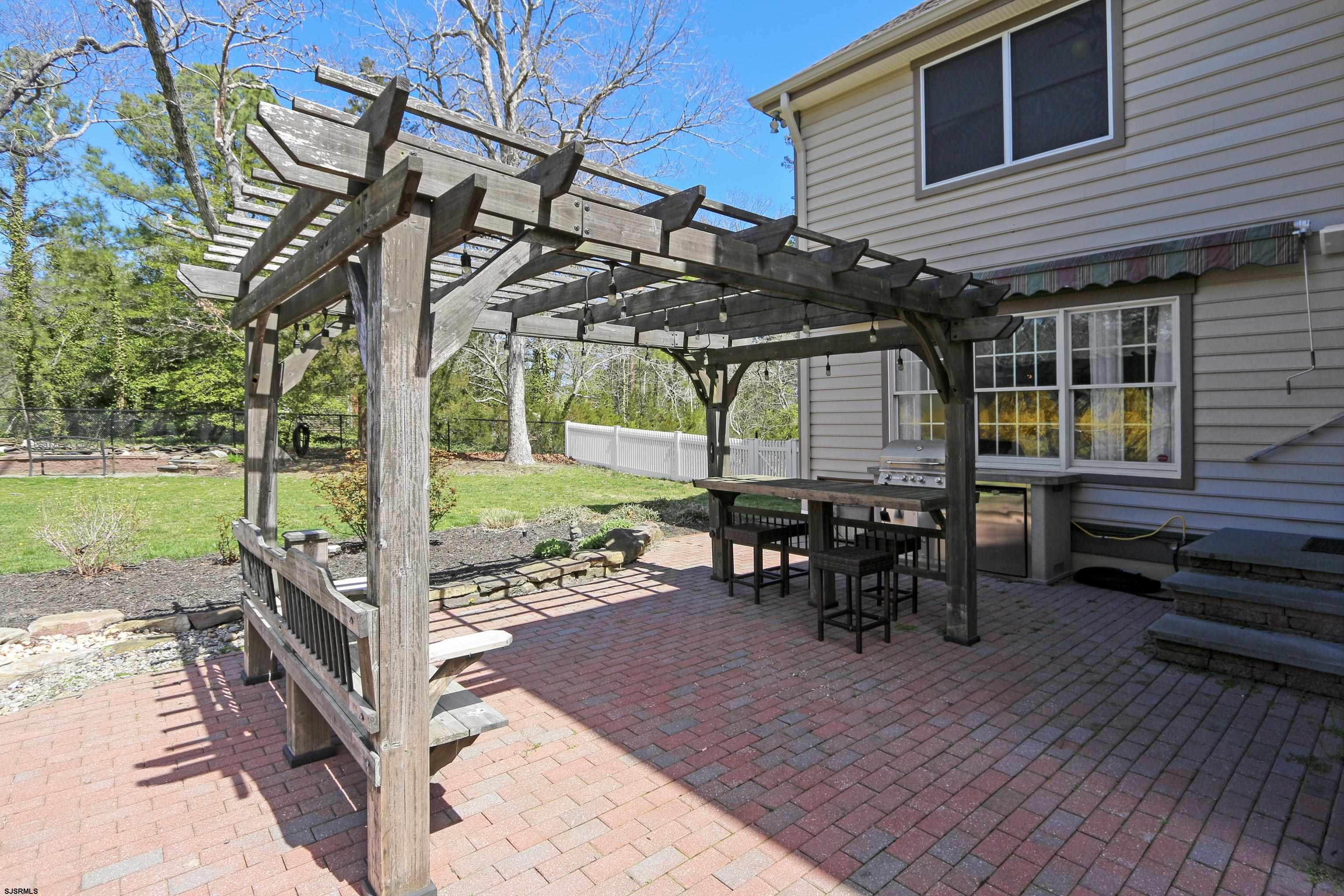 1322 Shore Road Palermo, NJ 08230 - Photo 43 of 56 a view of a patio with a table and chairs under an umbrella with a barbeque