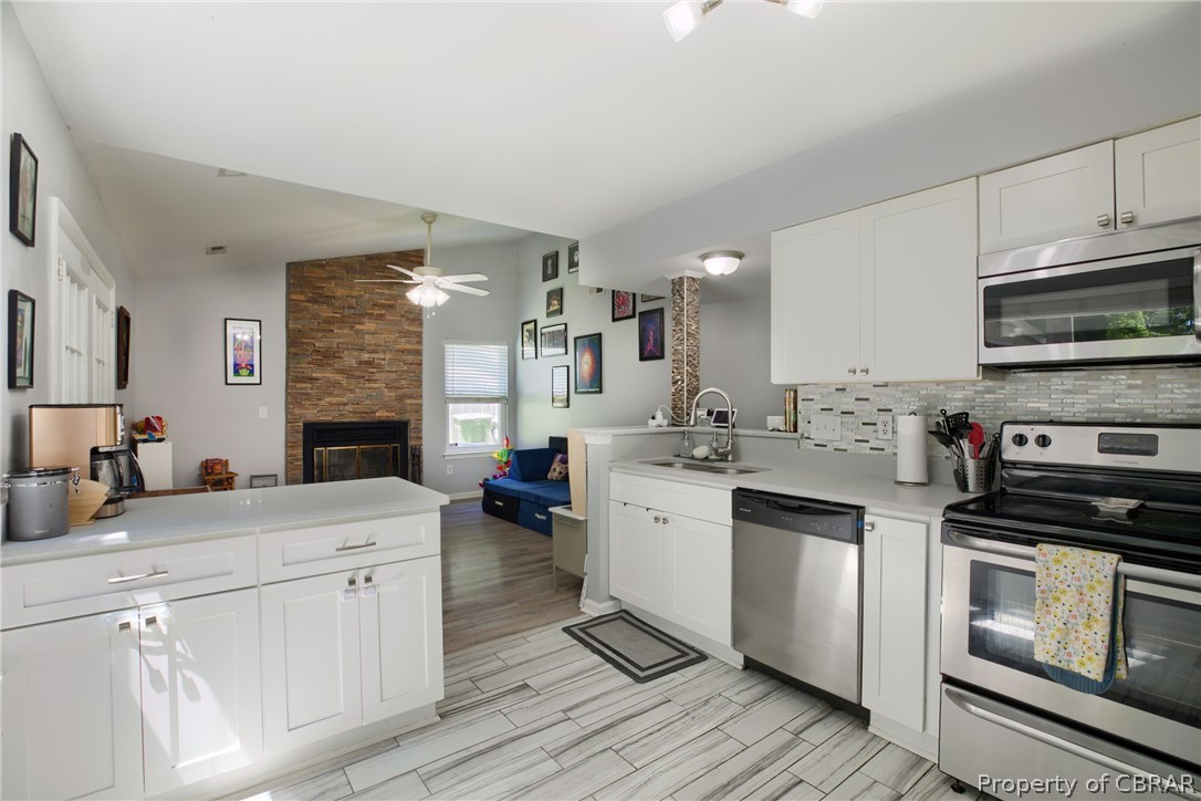 133 Springdale Way Hampton, VA 23666 - Photo 12 of 25 Kitchen featuring ceiling fan, sink, vaulted ceiling, appliances with stainless steel finishes, and a stone fireplace