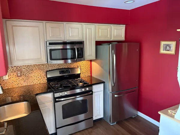 a kitchen with granite countertop a refrigerator stove and microwave