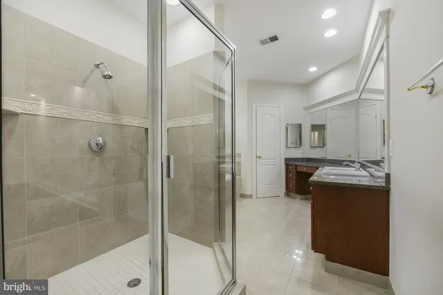a bathroom with a granite countertop sink a mirror and a shower