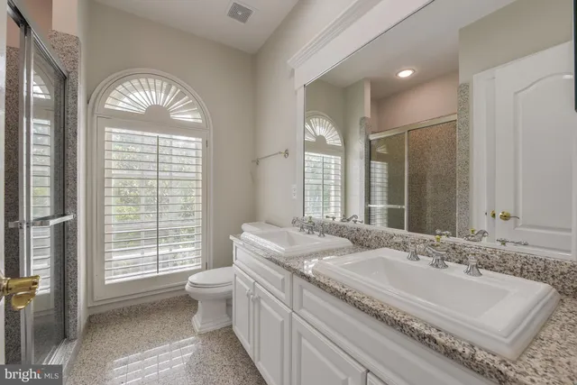 a en suite bathroom with a granite countertop tub a sink and a large mirror