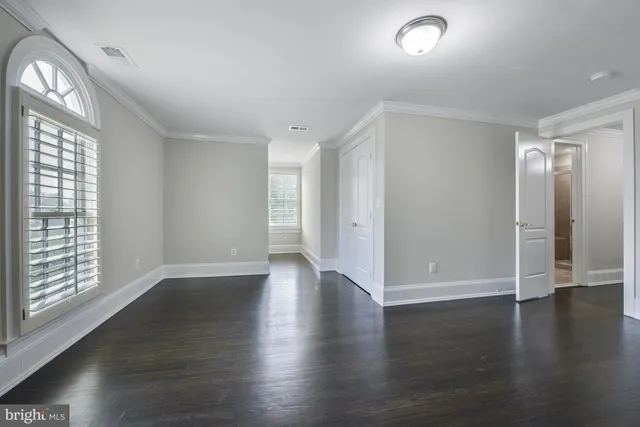 an empty room with wooden floor cabinet and windows