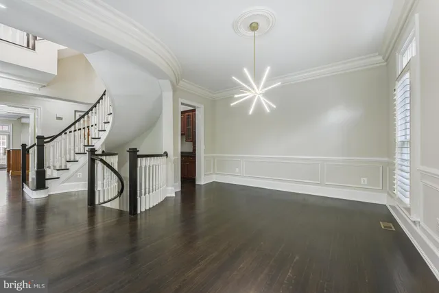 a view of an empty room with wooden floor and fan