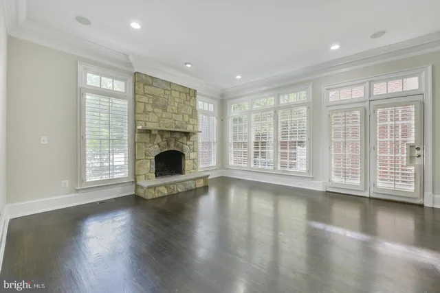 a view of an empty room with wooden floor and a fireplace