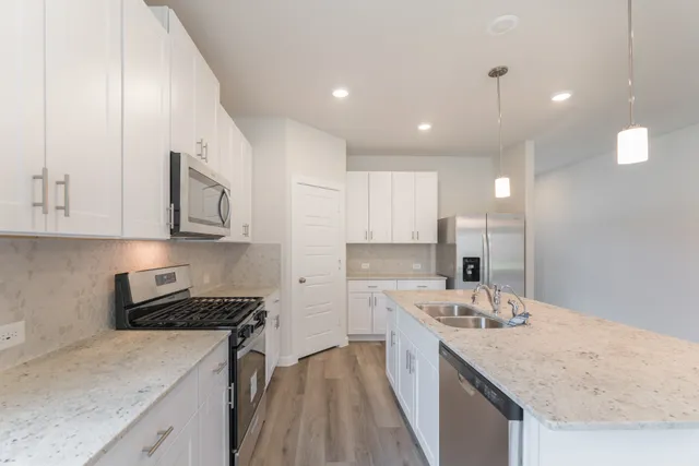 a kitchen with kitchen island a sink stainless steel appliances and white cabinets
