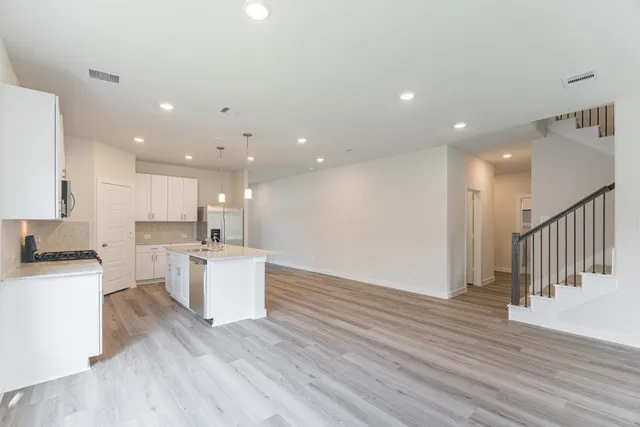 a large kitchen with stainless steel appliances lots of counter space and wooden floor