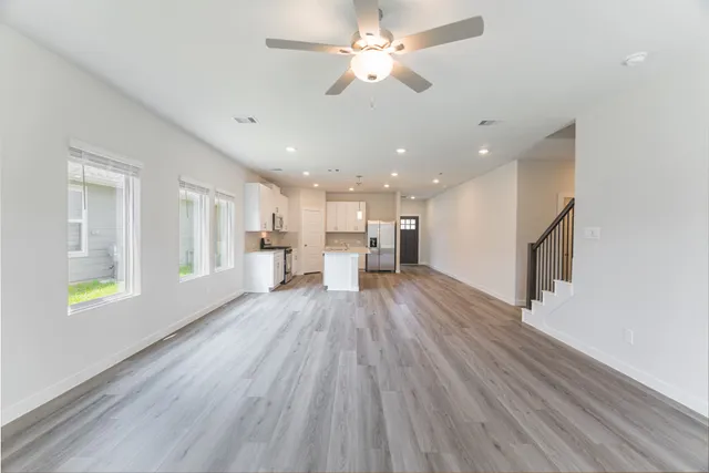 a view of empty room with wooden floor and fan