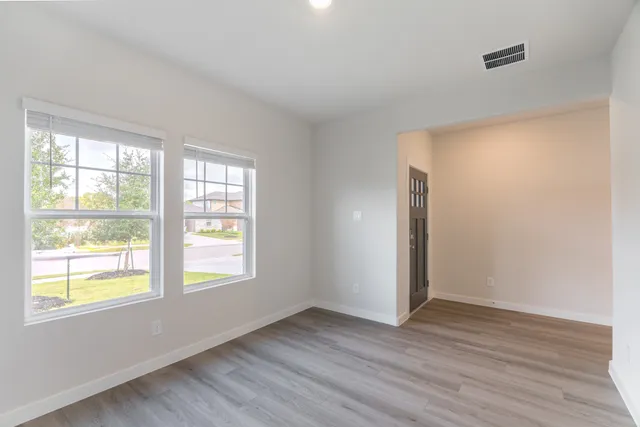 a view of an empty room with wooden floor and a window