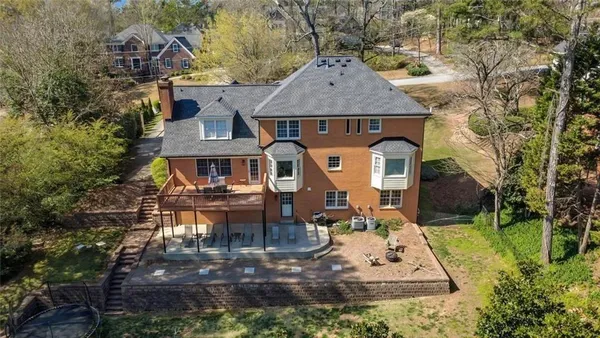 an aerial view of a house with swimming pool and large trees