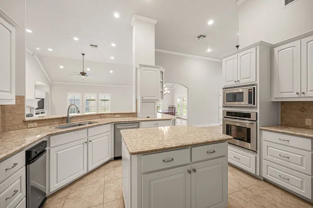 a kitchen with stainless steel appliances granite countertop a sink stove oven and white cabinets