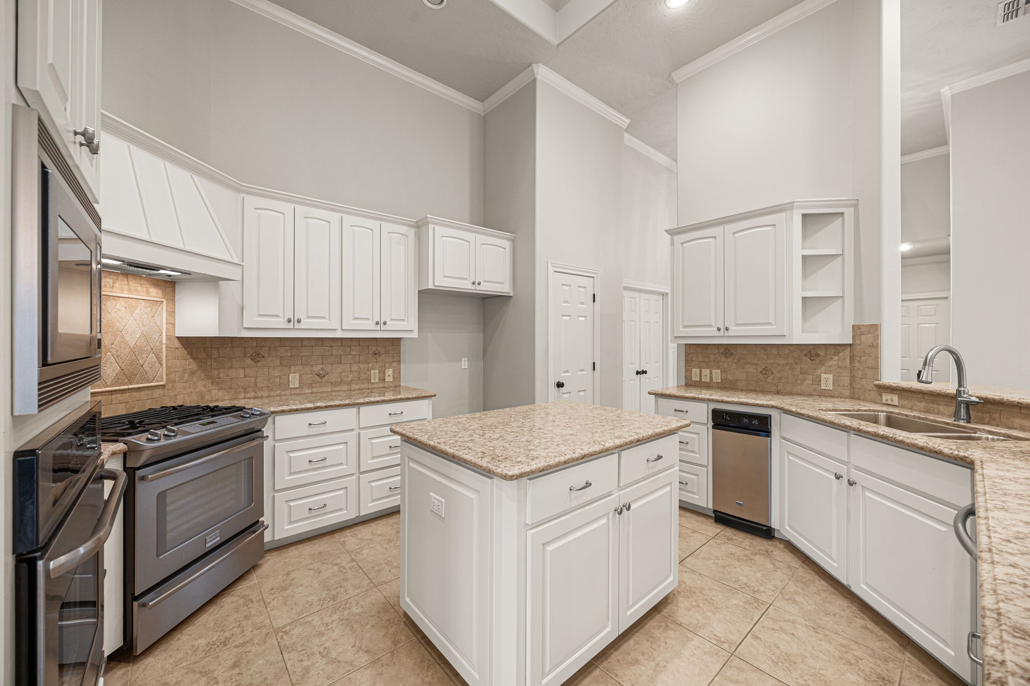1220 Travis Street Columbus, TX 78934 - Photo 16 of 39 a kitchen with granite countertop white cabinets and white appliances