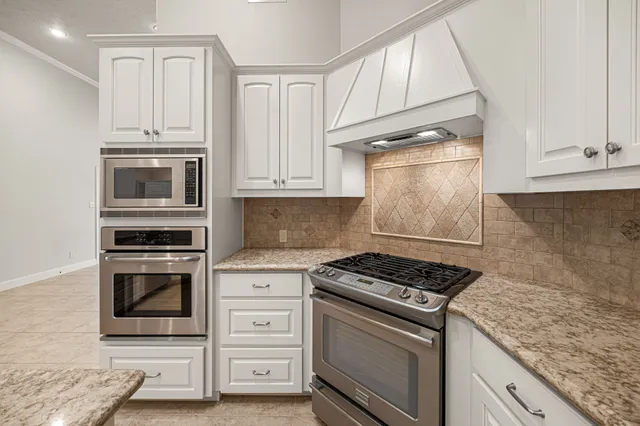 a kitchen with a sink dishwasher a stove and white cabinets