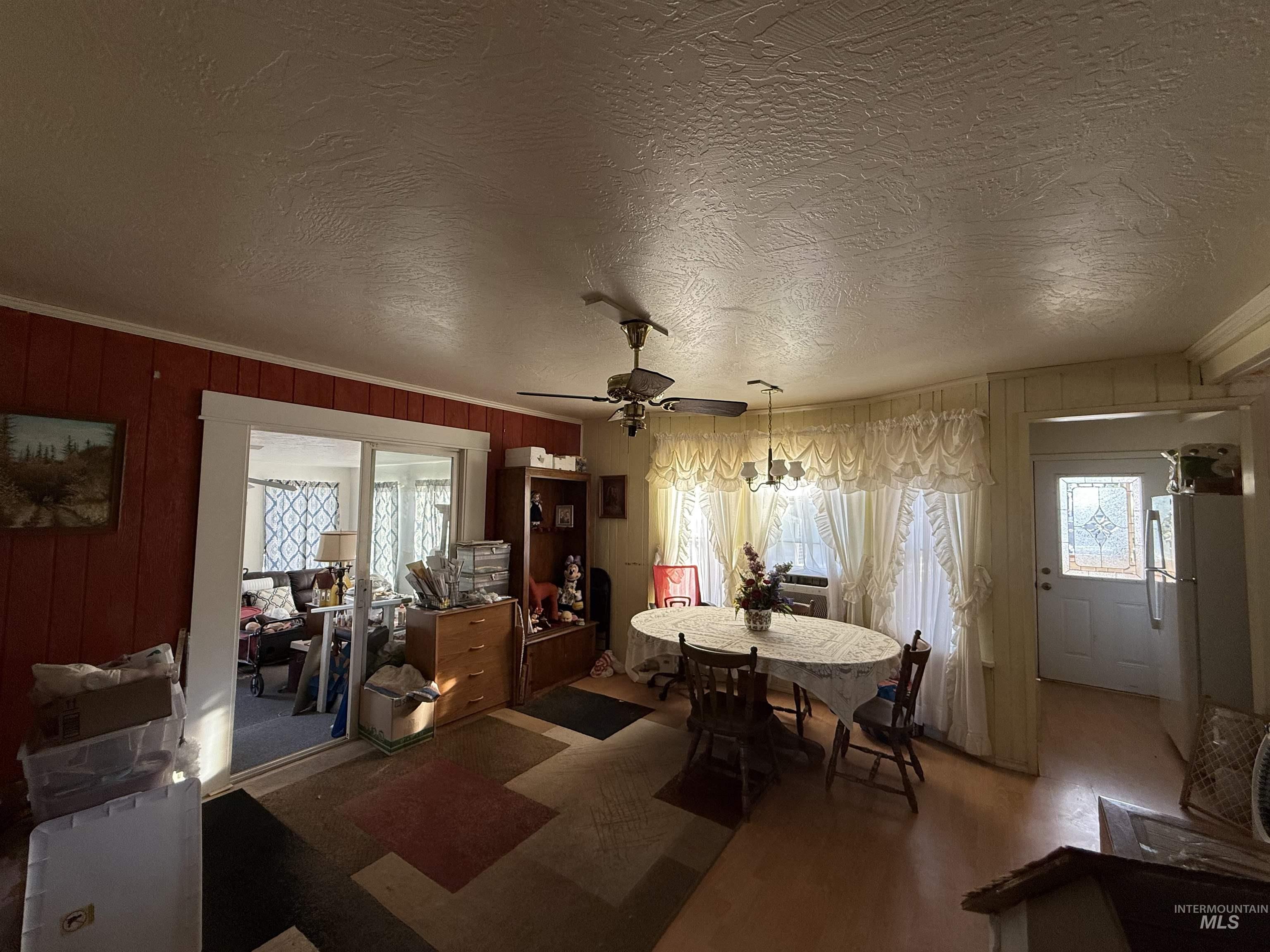 19241 West Homedale Road Caldwell, ID 83607 - Photo 32 of 35 Dining space featuring a textured ceiling, wooden walls, ceiling fan, wood finished floors, and ornamental molding