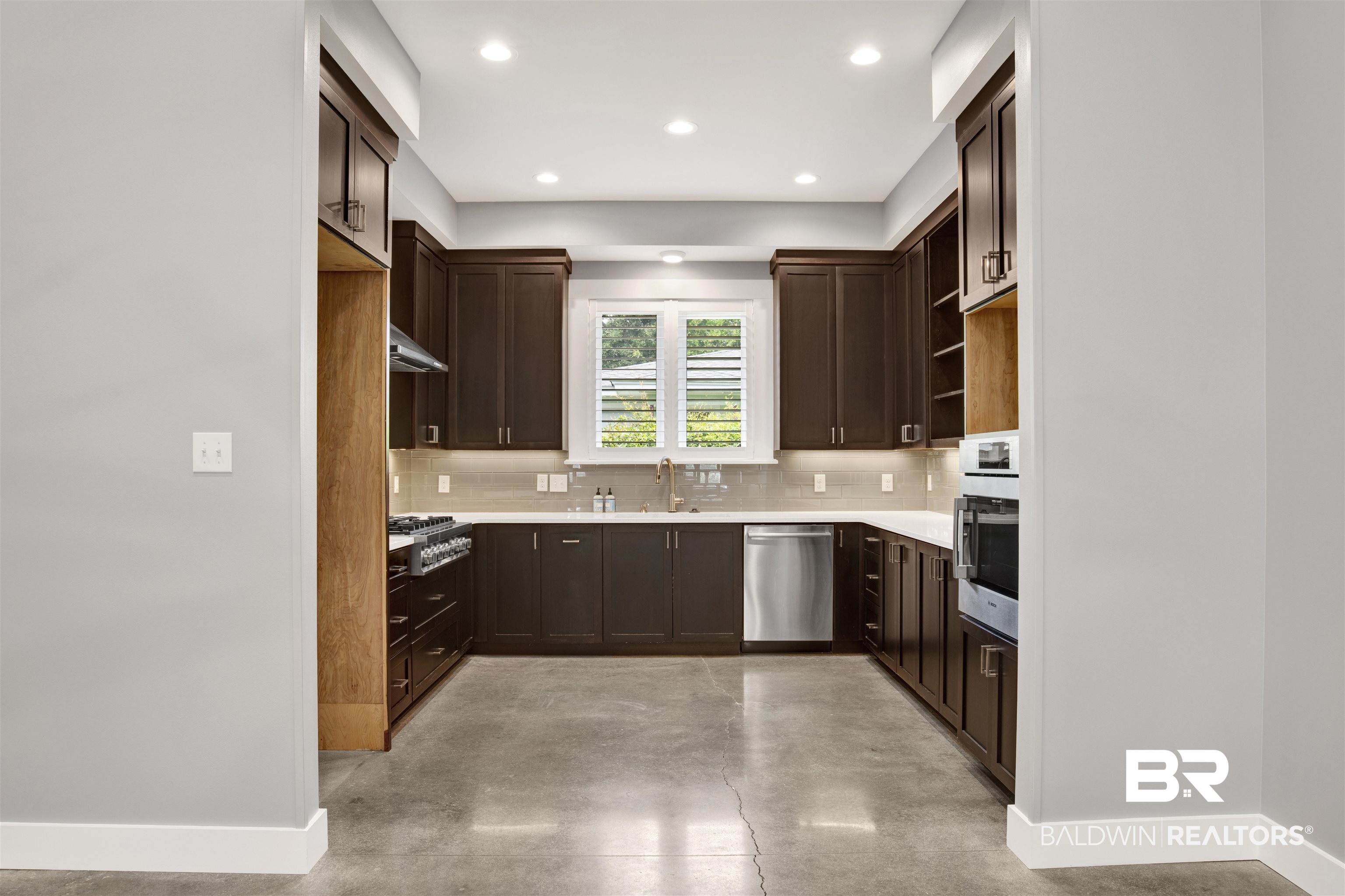 27980 Canal Road Orange Beach, AL 36561 - Photo 22 of 46 Kitchen with decorative backsplash, concrete floors, dark brown cabinets, appliances with stainless steel finishes, and recessed lighting
