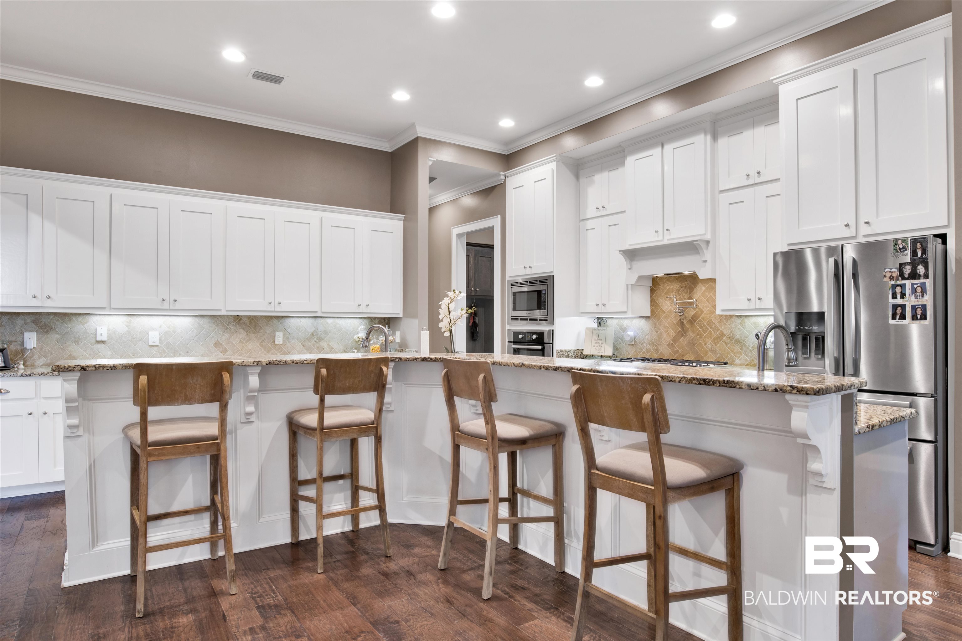 11244 Redfern Road Daphne, AL 36526 - Photo 20 of 50 Kitchen with dark hardwood / wood-style flooring, a large island with sink, a kitchen bar, and decorative backsplash