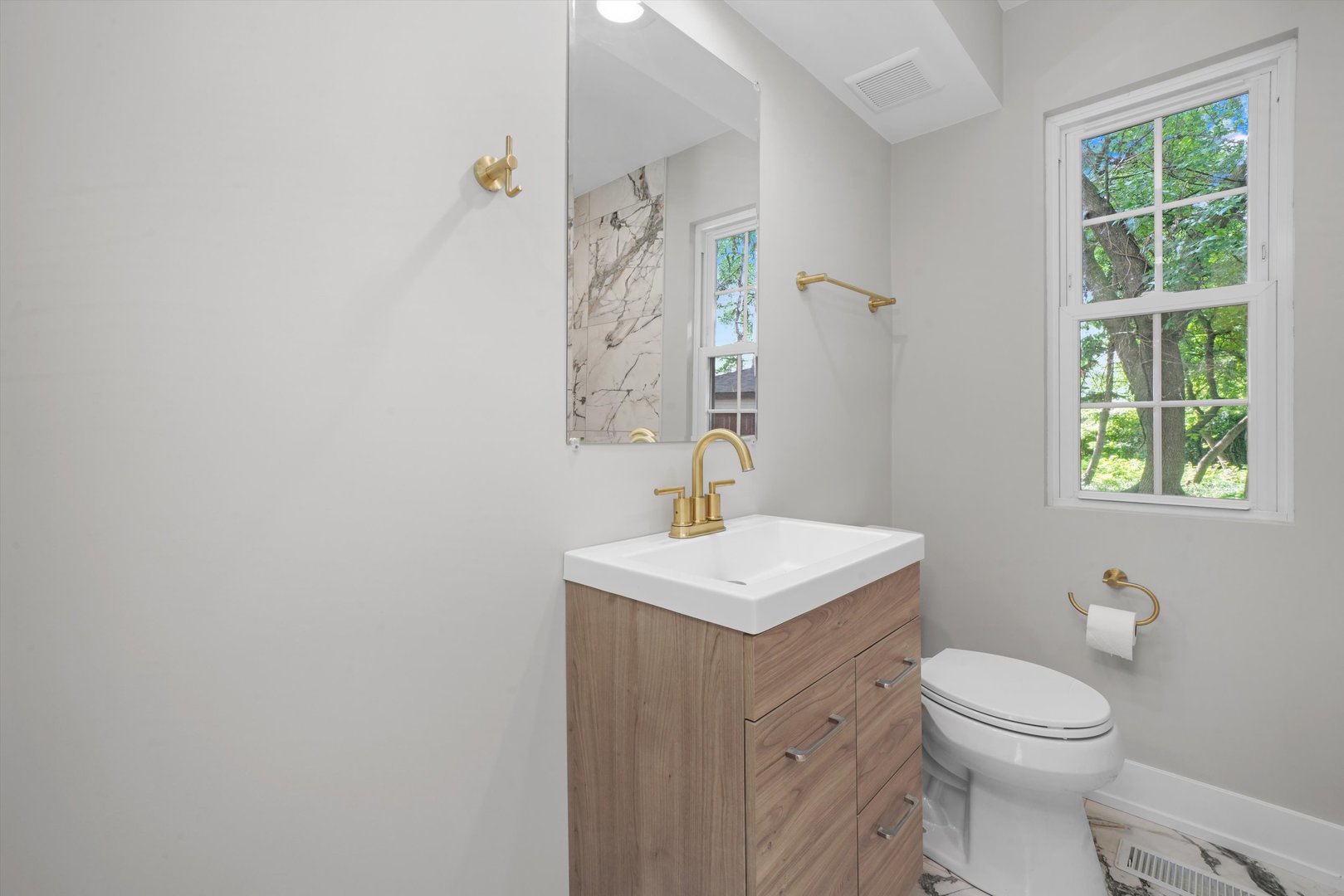 329 East Quincy Street Riverside, IL 60546 - Photo 18 of 39 a bathroom with a toilet a sink a mirror and a window