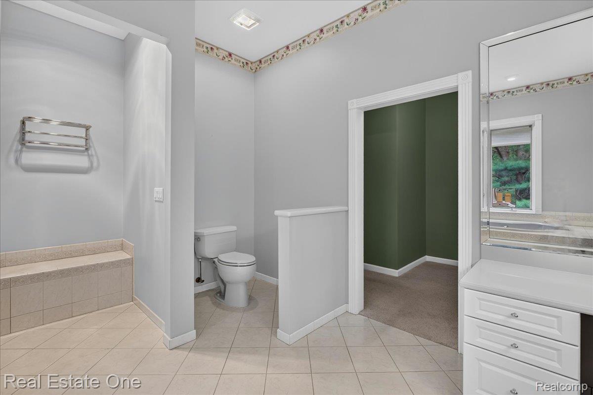425 Courtney Road Leonard, MI 48367 - Photo 47 of 89 Tiled flooring with a built-in bench, toilet area, and a vanity with integrated mirror