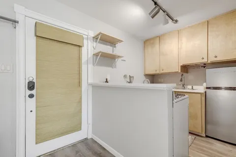 a view of cabinets a refrigerator and a stove in a kitchen