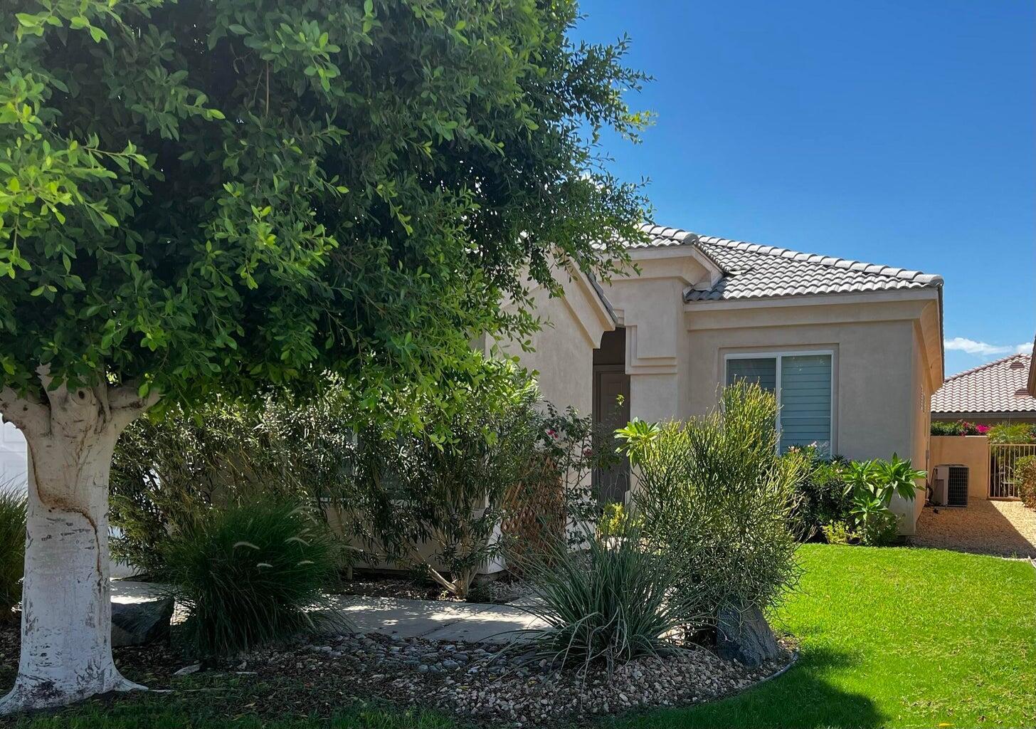 44725 Alexandria Vale Indio, CA 92201 - Photo 13 of 22 a view of a white house next to a yard with plants and trees