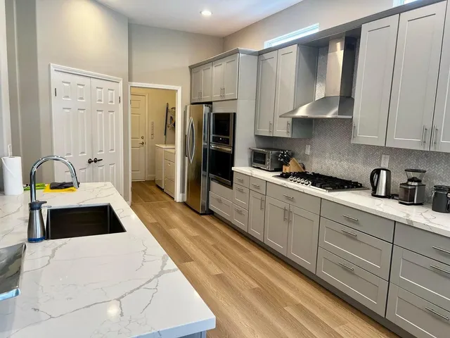 a kitchen with stainless steel appliances a stove a sink and white cabinets