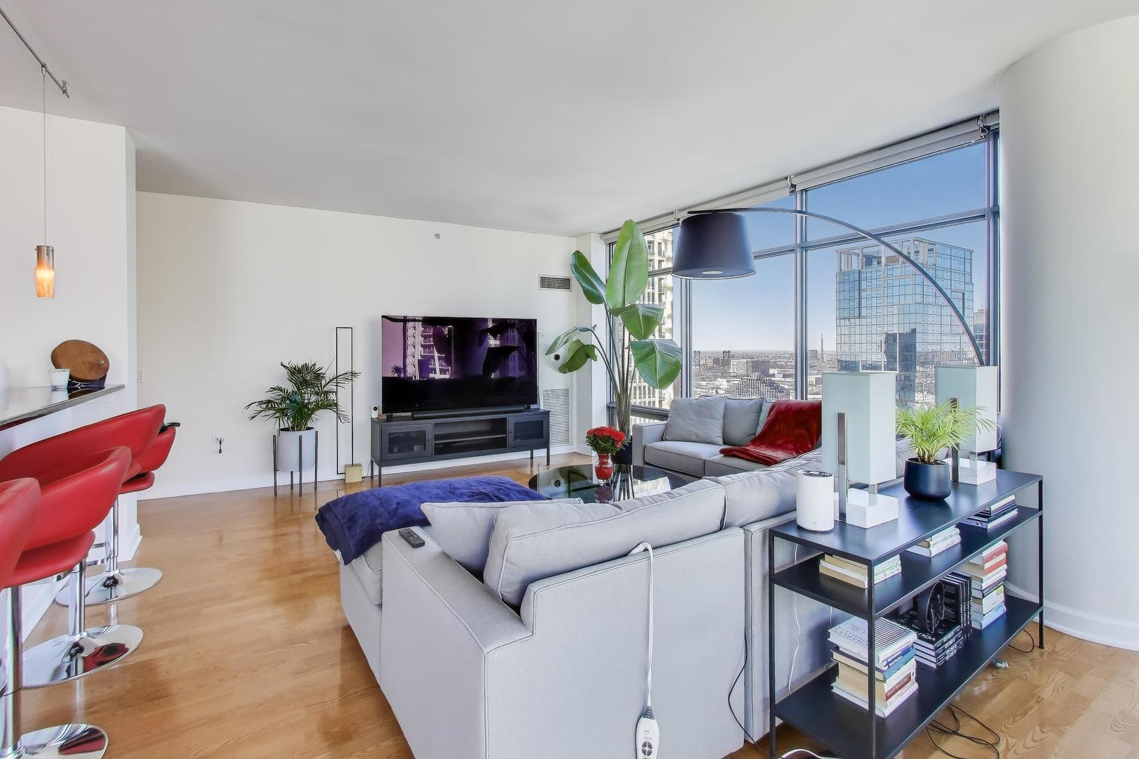 100 East 14th Street, Unit 2010 Chicago, IL 60605 - Photo 4 of 30 a living room with furniture a flat screen tv and a large window