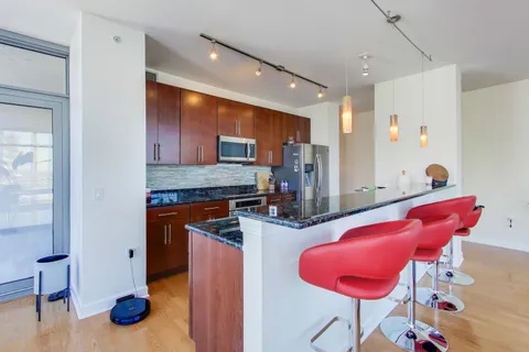 a kitchen with stainless steel appliances kitchen island granite countertop a refrigerator and a sink