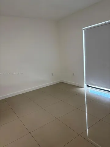 a view of a hallway with wooden floor and a bathroom