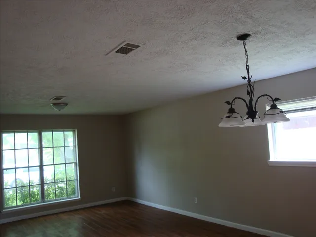 an empty room with wooden floor ceiling fan and window