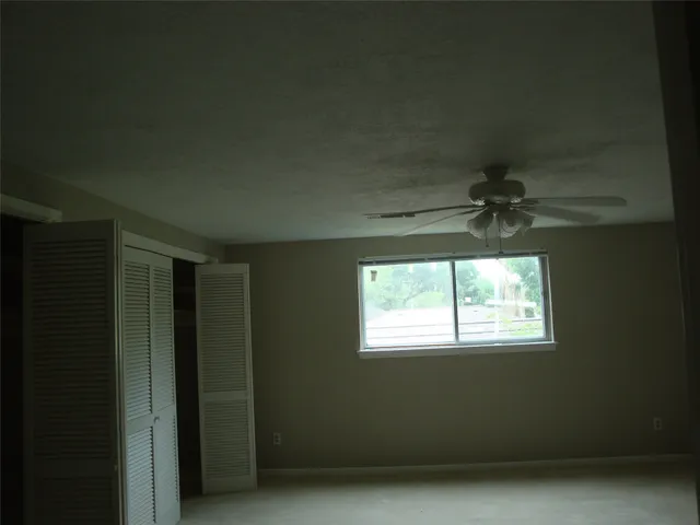 an empty room with a window and a ceiling fan