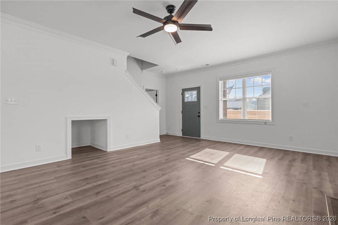 296 Persimmon Tree Drive Cameron, NC 28326 - Photo 4 of 43 an empty room with wooden floor chandelier fan and windows